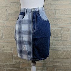 a mannequin wearing a skirt made out of old jeans and plaid fabric, on a brick wall