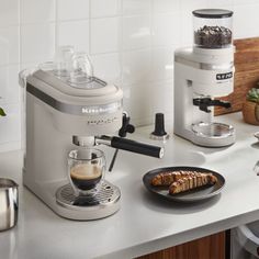 an espresso machine sitting on top of a counter next to a plate of food