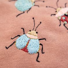 an embroidered fabric with bugs and ladybugs on it, as if they were from the 1950's or early 1960s's