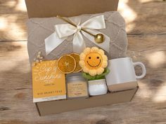 an open box containing coffee, oranges and other items on a wooden table with a white ribbon