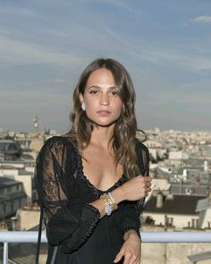 a woman standing on top of a roof with a handbag in her other hand