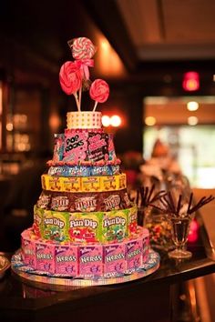 a multi - tiered cake decorated with candies and lollipops sits on a table