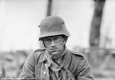 black and white photograph of an old man wearing a soldier's helmet while sitting at a table