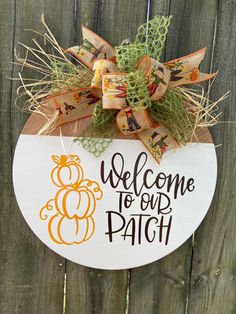 a welcome to our patch sign hanging on a wooden fence with grass and burlocks