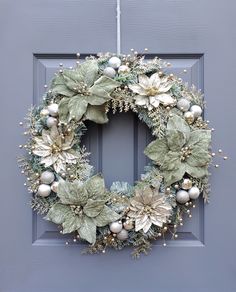 a christmas wreath hanging on the front door with balls and greenery around it's edges