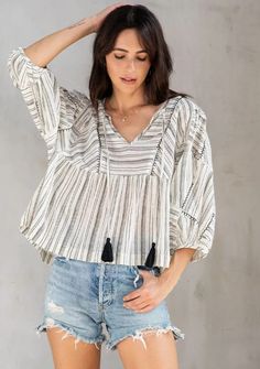 An ultra-flowy bohemian top made for warm days and nights. Designed in a cotton slub stripe, featuring exaggerated puff sleeves, tassel neckties, and a bib front. The hand-stitched embroidery elevates this effortless boho top. Bohemian Striped Tops For Vacation, Bohemian Cotton Blouse With Back Tassel Tie-up, Bohemian Blouse With Tassel Ties For Beach, Striped Cotton Blouse For Vacation, Fall Cotton Tops With Tassels, Cotton Tops With Tassels For Fall, Casual Cotton Blouse With Tassel Ties, Casual Cotton Blouse With Back Tassel Tie-up, Chic Beach Peasant Top With Relaxed Fit