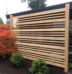 a wooden slatted fence in front of some bushes