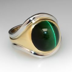 This handsome ring features a central band of eighteen karat yellow gold, bezel set with an oval cabochon cut, natural cat's-eye tourmaline. Two (2) platinum accent bands are attached to the outer edges of the gold band. The ring measures 20.1mm at the top, rises 10.2mm above the finger, tapering to 9.6mm wide and 1.6mm thick at the base of the European style shank. This ring is currently a size 9. Yellow Gold Cabochon Signet Ring, Yellow Gold Enamel Cabochon Ring, Yellow Gold Tourmaline Ring With Polished Finish, Yellow Gold Tourmaline Cabochon Ring, Mens Tiger Eye Ring, Natural Cat, Tourmaline Ring, September Birthstone, Oval Cabochon