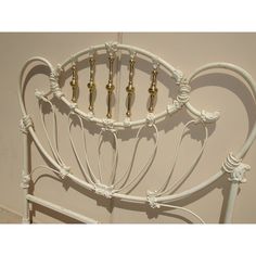 a white iron bed frame with four brass knobs