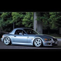 a silver sports car parked in front of some trees