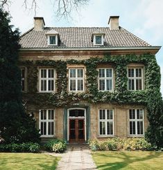 an old house with ivy growing all over it's walls and windows, along with a walkway leading to the front door