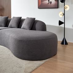 a large gray couch sitting on top of a hard wood floor next to a lamp