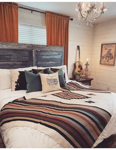 a bed with pillows and blankets on top of it next to a chandelier