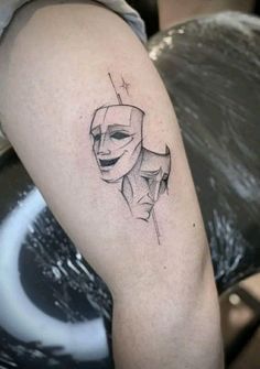 a woman's arm with a mask and cross tattoo on the left upper arm