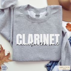 Show your marching band spirit with this clarinet fuels the soul crewneck sweatshirt. We print on warm and cozy Gildan brand sweatshirts. More band and orchestra instrument shirts available at my homepage https://www.etsy.com/shop/AbbyZachDesigns ----HOW OUR SHIRTS ARE MADE ----  * We use the process of DTG, which stands for direct to garment printing. We partner with a professional printer who applies ink directly into the shirt. (We do not use vinyl.) This gives you better quality and will not Fall Band Logo Crew Neck Sweatshirt, Fall Crew Neck Sweatshirt With Band Logo, Fall Band Merch Sweatshirt With Band Logo, Music-themed Long Sleeve Sweatshirt For Fall, Clarinet Shirts, Band Sweater, Music For The Soul, Brand Sweatshirts, Clarinet Music