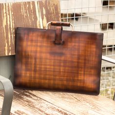 a brown briefcase sitting on top of a wooden bench