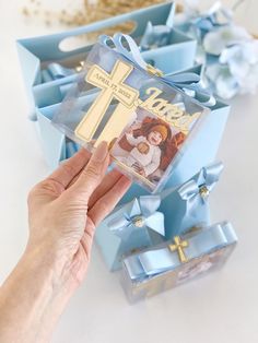 a person holding a small cross in front of blue boxes with other items on them