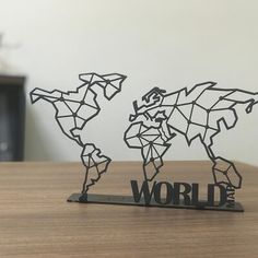 a metal world map sitting on top of a wooden table