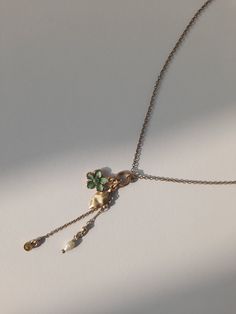 Adorn yourself with the whimsical charm of nature with this delightful necklace featuring four dangling treasures. A petite green flower, a delicate leaf, a shimmering stone, and a lustrous pearly accent sway gracefully from the dainty chain, creating a captivating ensemble that captures the essence of natural beauty. Whether worn alone or layered with other favourites, this enchanting piece adds a touch of elegance and allure to any look. Green Bohemian Jewelry With Clavicle Chain, Bohemian Green Clavicle Chain Jewelry, Bohemian Green Jewelry With Clavicle Chain, Green Necklaces With Clavicle Chain And Flower Pendant, Green Dangle Charm Necklace, Green Dangle Charm Necklaces, Green Charm Necklace With Dangling Charms For Gift, Green Jewelry With Dangling Charms As Gift, Dainty Clavicle Chain Necklace For May Birthstone