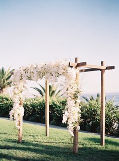 an outdoor ceremony setup with white flowers and greenery