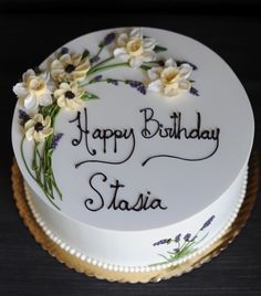 a white birthday cake with flowers and writing happy birthday stasia on the side