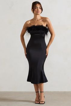 a woman wearing a black dress with feathers on it