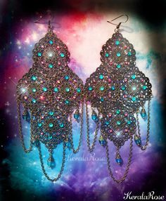 These exotic chandelier earrings are made with filigree pendants decorated with Teal & Fuchsia Swarovski rhinestones. Draped chains and Teal blue crystal beads hang from the design. There are 72 hand set Swarovski and Preciosa Rhinestones on this pair!  These can be worn everyday comfortably because they are lightweight for their size!  They're available with Posts, Clip-Ons or French Wires. Metal Finishes Available: -Bronze (as pictured) -Silver -7" Long (including piercing) x 3" Wide -0.4 oz.. Affordable Blue Bohemian Chandelier Earrings, Bohemian Dangle Chandelier Earrings For Parties, Bohemian Chandelier Dangle Earrings For Parties, Bohemian Party Chandelier Dangle Earrings, Jeweled Dangle Chandelier Earrings, Bohemian Jeweled Chandelier Earrings As Gift, Bohemian Teardrop Chandelier Earrings For Party, Ornate Chandelier Earrings For Festivals, Bohemian Jeweled Crystal Earrings For Party