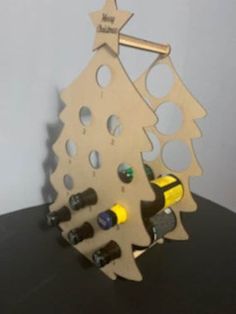 a wooden christmas tree with wine bottles in the shape of a bottle holder on a table