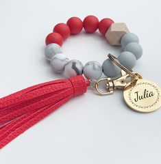 a tasseled bracelet with a personalized charm and a name tag on it