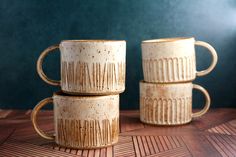 three coffee mugs sitting on top of a wooden table