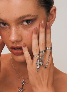 a woman with her hands on her face and rings around her neck, posing for the camera