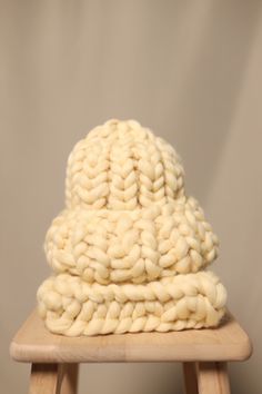 a white knitted hat sitting on top of a wooden stool