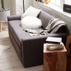 a living room with a gray couch and some books on the table next to it