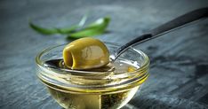 an olive in a glass bowl with a spoon