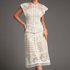 This lace midi dress will fill any of your little white dress needs, from your bridal shower to your after party! Sheer mesh, embellished with gorgeous lace creates a high, round neck and a fitted bodice with scalloped edges and cap sleeves. A high, fitted waist sits above an A-line midi skirt that has tiers of scalloped edges. Style this with strappy heels and simple accessories to complete the look.No StretchMedium WeightSize runs small,recommend one size upFabric: 100% Polyester,Lining: 100% Lace Patchwork Midi Dress For Wedding, Elegant Midi Dress With Delicate Lace For Party, Wedding Midi Dress With Lace Patchwork, Elegant Party Midi Dress With Delicate Lace, Feminine Lace Trim Midi Wedding Dress, Lace Midi Dress With Illusion Neckline, Midi Lace Dress With Illusion Neckline, Feminine Lace Trim Midi Dress For Wedding, Elegant Lace Top Midi Dress