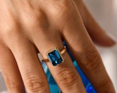 a woman's hand with a ring on it and a blue stone in the middle