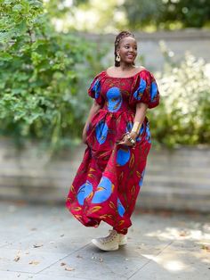 A beautiful statement dress with side pockets in a contemporary African print in a vibrant red with a bold floral pattern. It has smocking from the bust to the waist with a full skirt to the dress and adjustable exaggerated puff sleeves which can be worn off or on shoulder. An easy to wear pull on piece that may be styled for an informal outing or a formal occasion by selecting the appropriate accessories and footwear.100% Cotton. Handmade in Ghana. HAVE YOU CHECKED YOUR MEASUREMENTS AGANST THE Dress With Puff Sleeves, Maxi Skirt Dress, Statement Dress, African Design Dresses, Jumpsuit Trousers, African Design, Full Skirt, Vibrant Red, Skirt Top