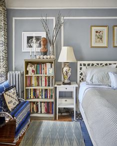 a bed room with a neatly made bed and a book shelf filled with books next to a lamp