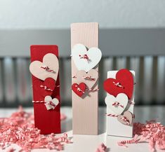 three valentine's day decorations made out of wood sticks and paper hearts on a table