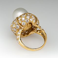 This magnificent cocktail ring is centered with one (1), post set, cultured South Sea pearl. The pearl tops a domed setting is bead set sixty-four (64), bead set, round brilliant cut diamonds. The ring has a split shank design and is accented with seven (7), bead set, round brilliant cut diamonds on each side. The ring measures 21.7mm at the top, rises 18.6mm above the finger, tapering to 2.4mm wide and 1.1mm thick at the base of the shank. The ring is currently size 7. Elegant White Domed Rings, Elegant White Domed Jewelry, Round Diamond Pearl Ring, Luxury Domed Jewelry With Brilliant Cut, Elegant Domed Rings For Formal Occasions, Elegant Formal Domed Rings, Formal Fine Jewelry Pearl Ring With Pearl Drop, Luxury Pearl Drop Ring For Formal Occasions, Luxury Pearl Ring For Evening