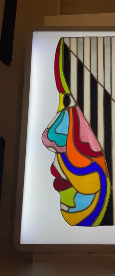 a colorful painting on the side of a wall next to a light box with an image of a woman's face