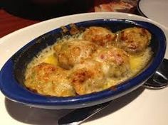 a blue bowl filled with food on top of a white table next to a fork