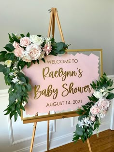 a welcome sign for a baby shower with flowers and greenery around it on an easel