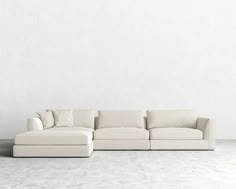 a white couch sitting on top of a cement floor next to a wall with a plant in it