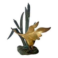 a gold bird statue sitting on top of a green plant