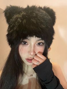 a woman with long black hair wearing a furry hat and gloves on her head is posing for the camera