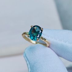 a close up of a person's hand holding a ring with a blue stone