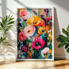 an art print of colorful flowers on a white wall next to a potted plant