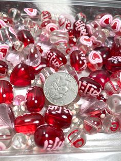 a penny sitting on top of a pile of red and white glass bead beads