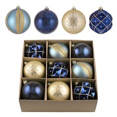 an assortment of blue and gold christmas ornaments in a cardboard box on a white background